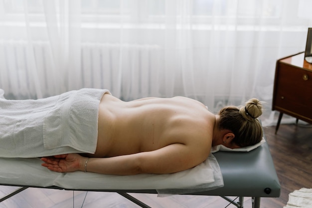 Young fat woman getting massage treatment in day spa cabinet