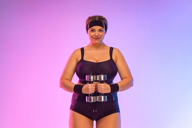 Молодая толстая спортсменка Бодипозитивный фитнес Девушка хочет похудеть с гантелями Фото для рекламного дизайна продуктов для похудения и фитнес-оборудования