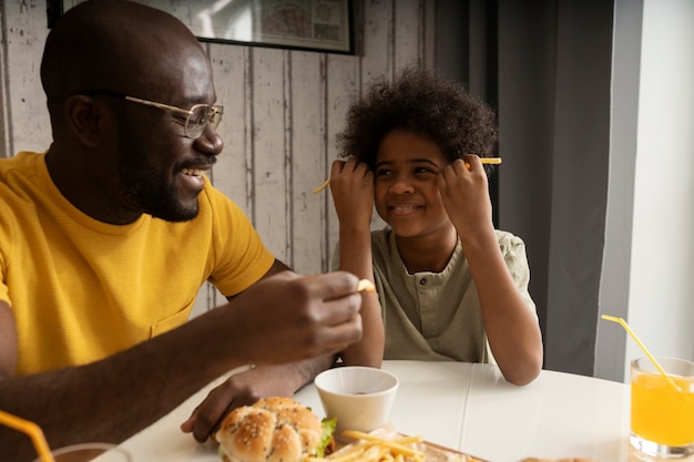 ハンバーガーとフライドポテトを一緒に持っている若い父と息子