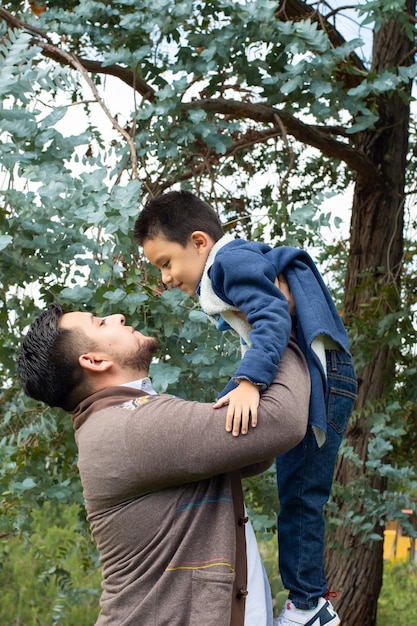 彼のかわいい子供を運ぶ若い父親