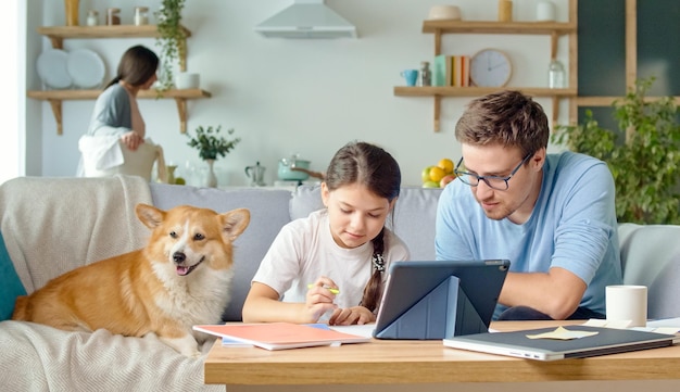 Young father helping his cute daughter schoolgirl with research the parent explains the daughters di...