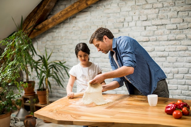 若い父親と彼のかわいい娘が家庭の台所で生地を作る