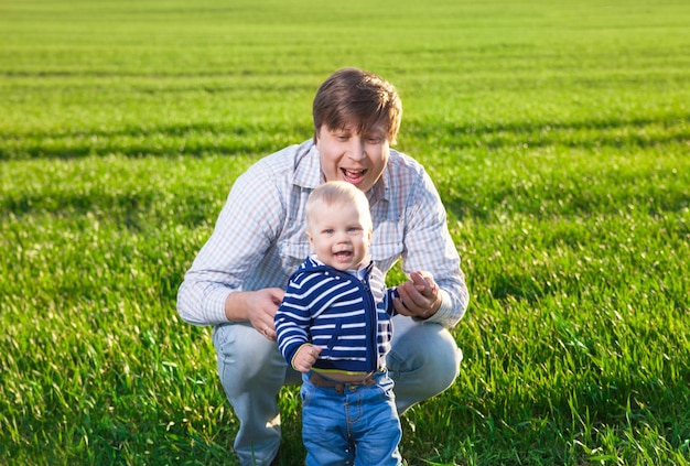 Photo young father and his son having fun playing on green field