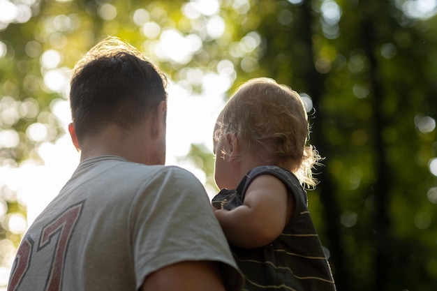 Photo young father holding his little son in his arms in the park