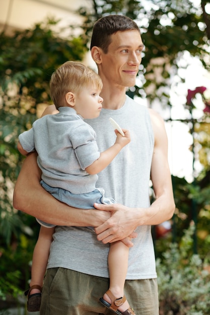Young father holding his little son in his arms while standing in the city outdoors