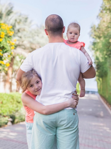 young father hugs his daughters in the garden