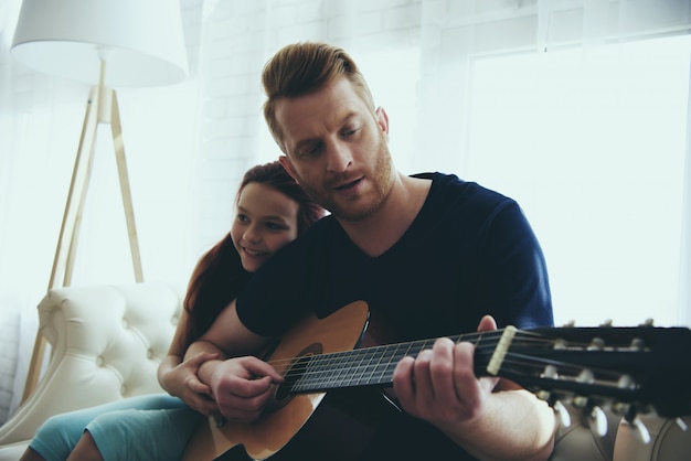 Young father is teaching little daughter to play.