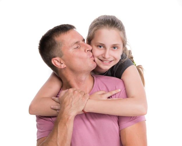 Young father kissing smiling daughter on a white wall