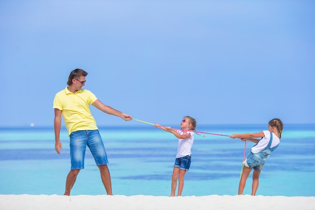 Young father and little girls have fun together during tropical vacation