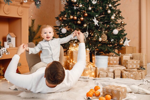 Young father and little son lay near Christmas tree and playing