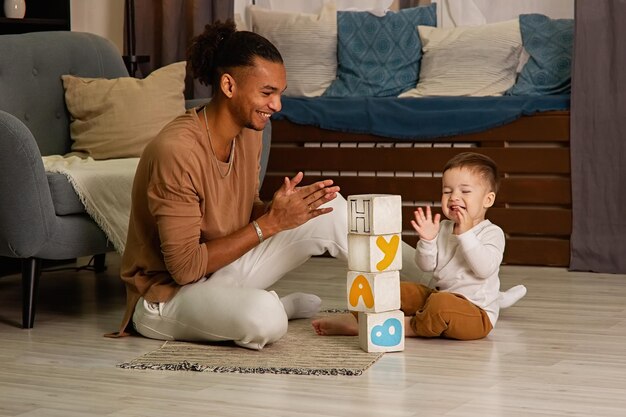 Young father and little son playing cubes on the floor of the room