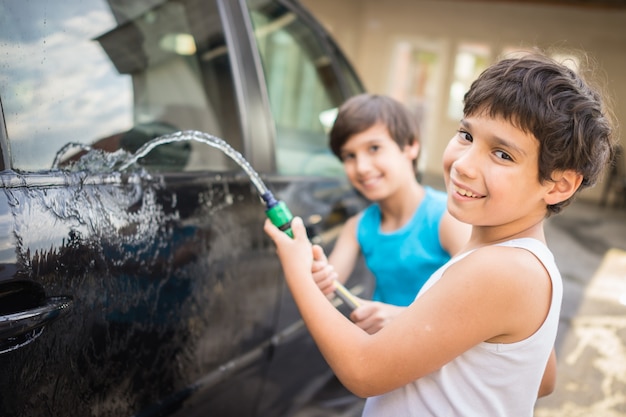 Photo young father and little sons washing car