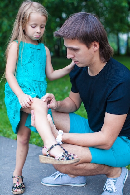 Young father pities his little daughter, who hurt her leg