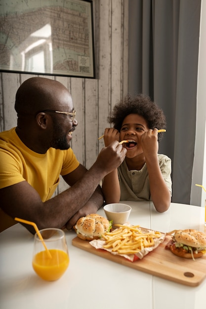 ハンバーガーとフライドポテトを一緒に持っている若い父と息子