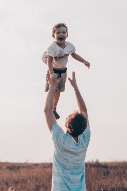 Il giovane padre vomita il suo figlio carino e piccolo all'aria aperta. festa del papà, padre e figlio di suo figlio che giocano e abbracciano all'aperto.