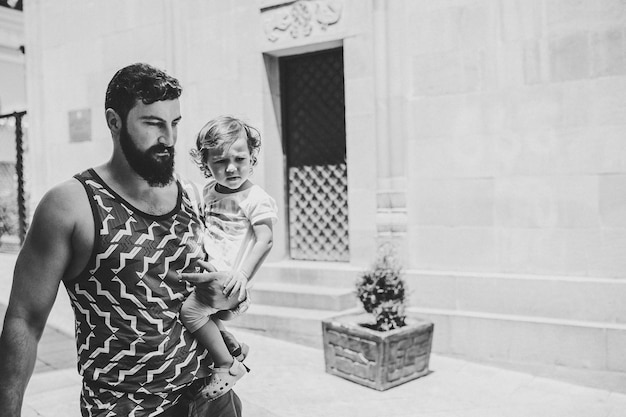 Young father walking with little daughter outdoors on streets in city of Tbilisi in the capital of Georgia on spring day Dad and girl travel on excursion in old town black and white photo