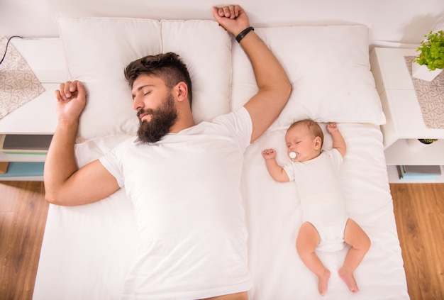 Giovane padre con un bambino nel letto di casa.