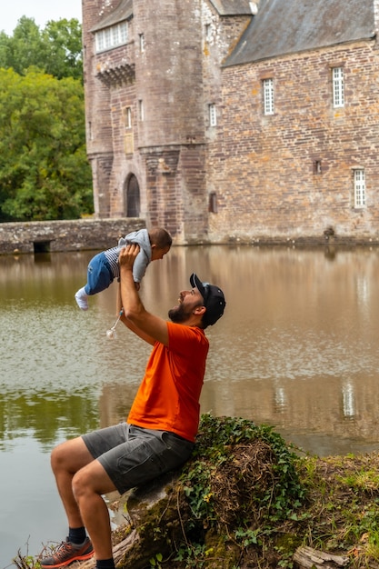 A young father with his baby visiting the medieval lakeside Chateau Trecesson, CampÃÂÃÂ©nÃÂÃÂ©ac commune in the Morbihan department, near the Broceliande forest.