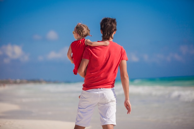 Young father with little girl look at the sea