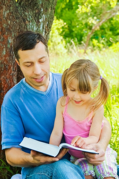 聖書を読んでいる小さな娘を持つ若い父親