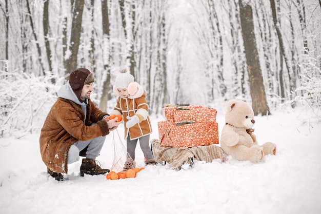 Young father with toddler daughter standing in winter forest