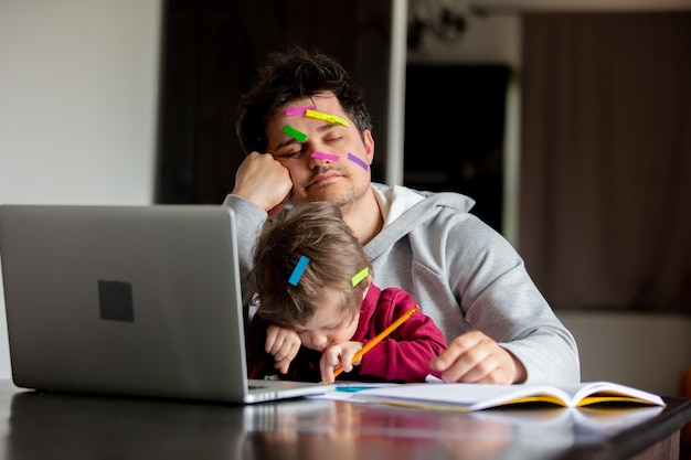 Фото Молодой отец работает за компьютером дома с ребенком