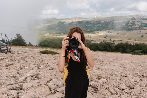 용감한 젊은 여성 사진 작가는 심연 근처 산에서 높은 관광객입니다. 활동적인 레크리에이션 산을 등반