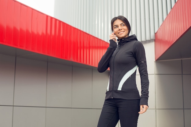 Young female active exercise workout on street outside using smartphone