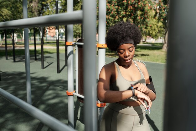 Young female in activewear looking at smartwatch on her wrist