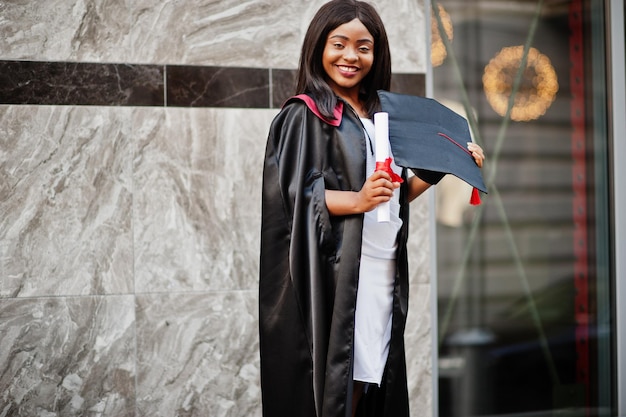 Young female african american student with diploma poses outdoorsxA