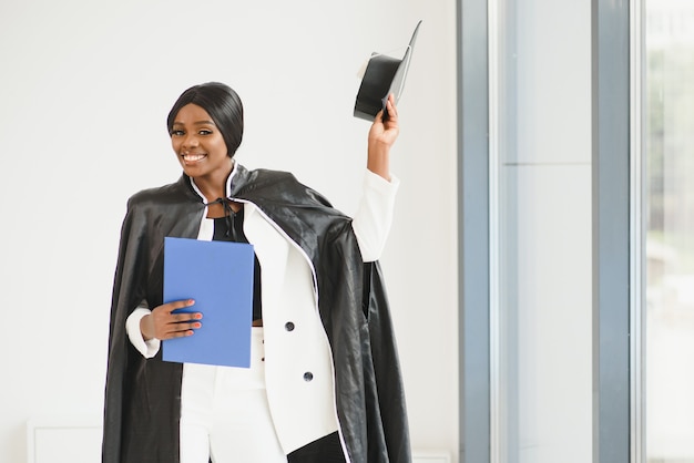 卒業証書を持つ若い女性のアフリカ系アメリカ人の学生。