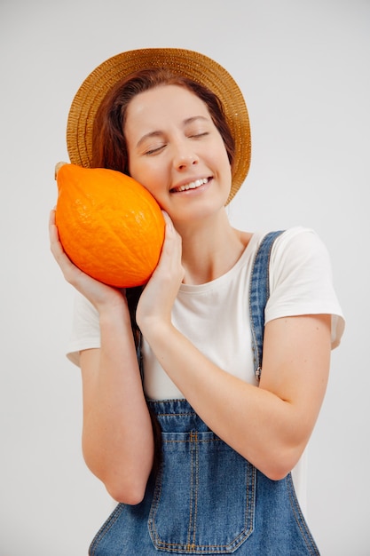 Young female agricultural farmer smiles while clutching a small ripe pumpkin concept of harvesting