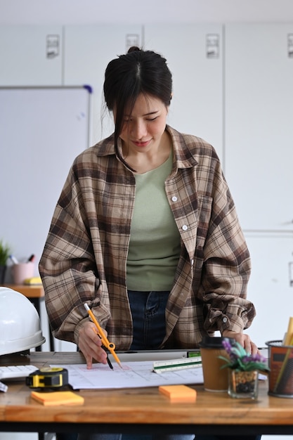 사무실에서 청사진 작업을 하는 젊은 여성 건축가.