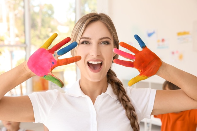 Young female art teacher with hands in paint indoors