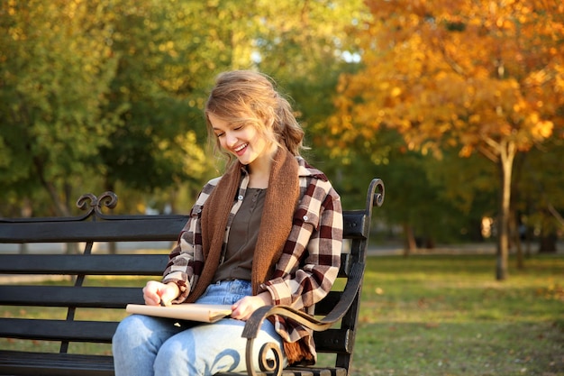 Photo young female artist drawing sketch while sitting on bench in beautiful park