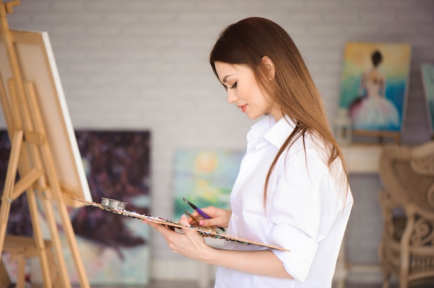 Young female artist painting picture in studio