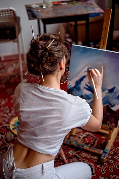 Молодая художница рисует картину в студии