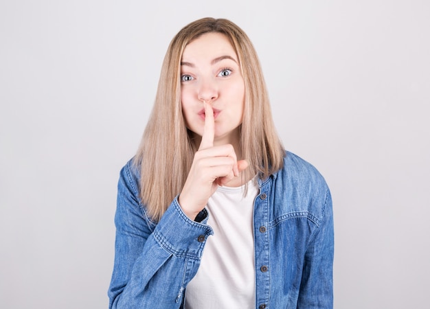 Young female asking to be quiet with finger on lips.