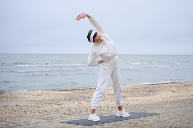 Young female athlete doing her meditation at the beach High quality photo