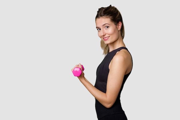 Giovane atleta femminile che solleva pesi focalizzata e determinata nello studio indoor