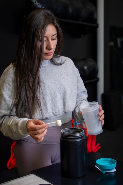 Young female athlete preparing protein after her workout