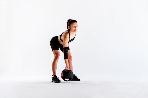 Young female athlete training in a gym using sport equipment