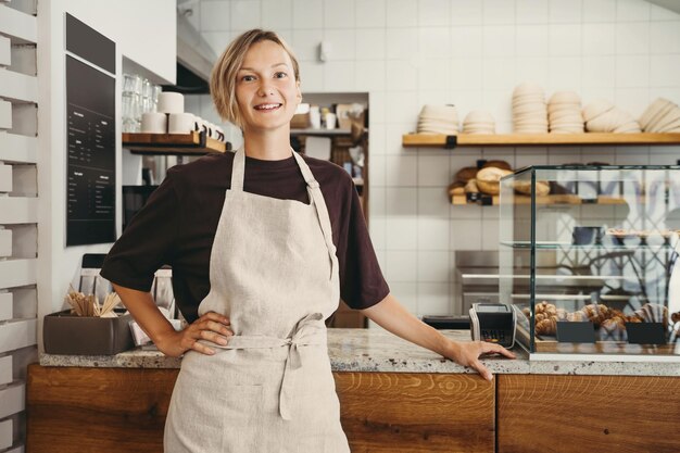 Фото Молодая женщина-пекарь-предприниматель, стоящая у прилавка пекарни и кафе