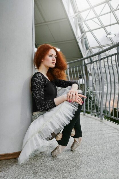 Photo young female ballerina resting in an indoors botanical garden