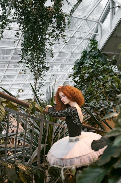 Young female ballerina stretching in an indoors botanical garden