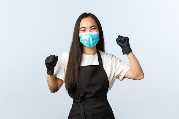 Young female barista wearing protective mask