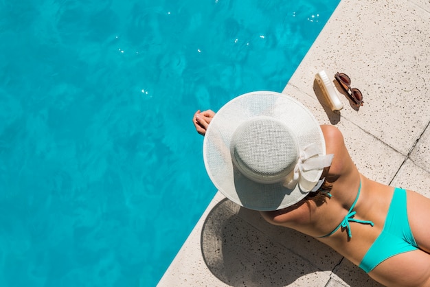 Giovane donna in bikini che prende il sole a bordo piscina