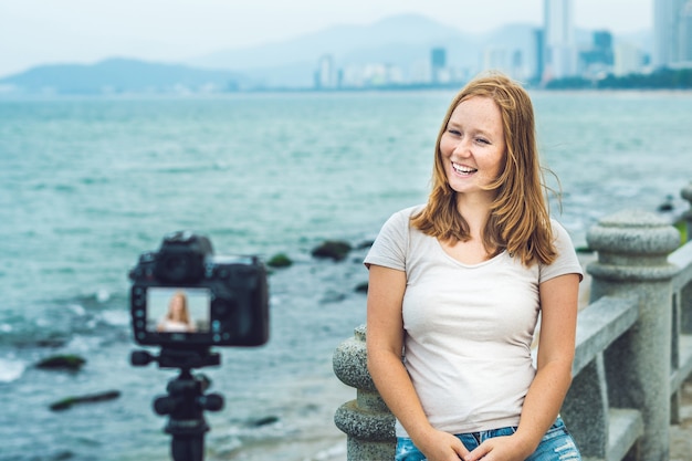 Young female blogger filming by the sea