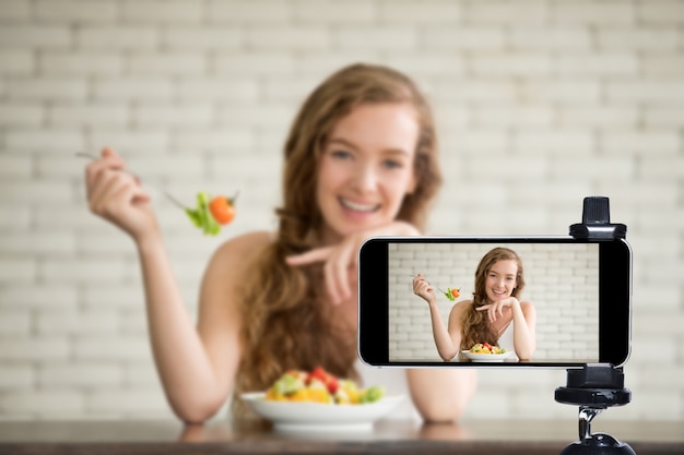 Giovane blogger e vlogger e influencer online in diretta streaming uno show di cucina sui social media utilizzando uno smartphone