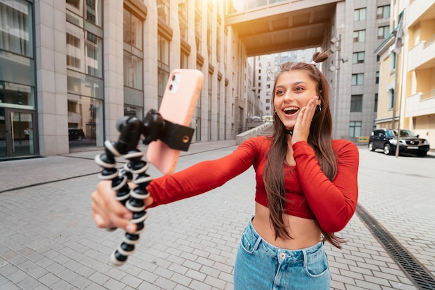 Young female blogger with smartphone streaming on the street